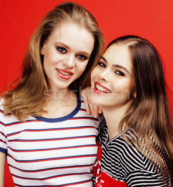 Stock photo: two best friends teenage girls together having fun, posing emotional on red background, besties happ