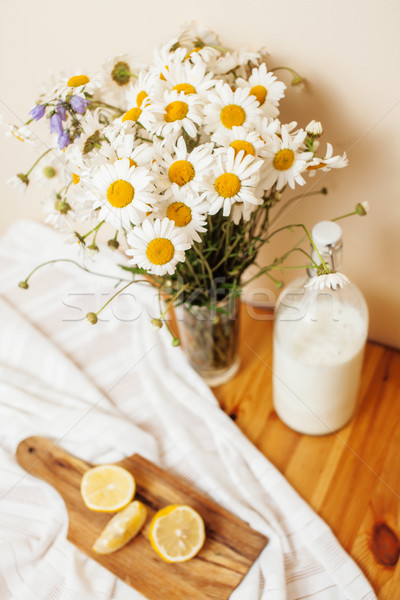 Simply stylish wooden kitchen with bottle of milk and glass on table, summer flowers camomile, healt Stock photo © iordani