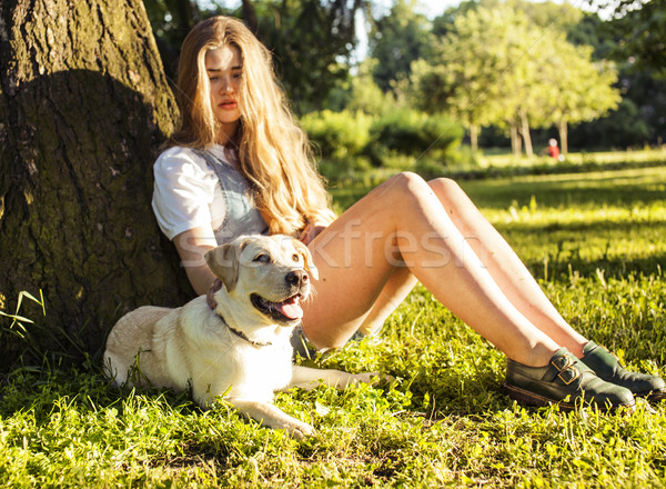 young attractive blond woman playing with her dog in green park  Stock photo © iordani