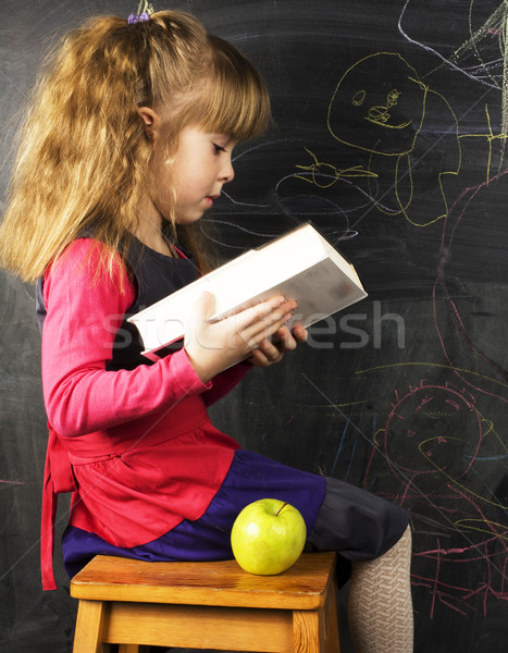 portrait of cute little girl with book and green apple near blac Stock photo © iordani