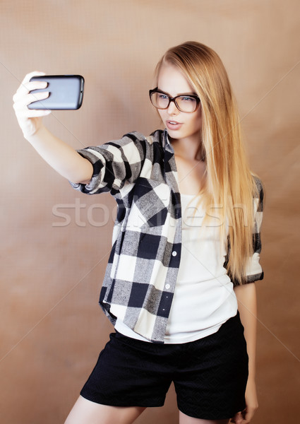young pretty blond hipster girl making selfie on warm brown background, lifestyle people concept Stock photo © iordani
