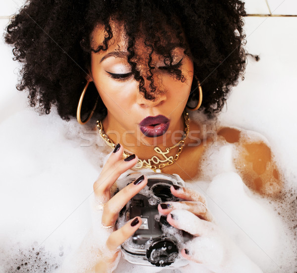 young afro-american teen girl laying in bath with foam, wearing  Stock photo © iordani