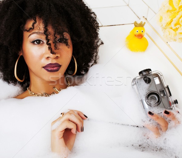 young afro-american teen girl laying in bath with foam, wearing  Stock photo © iordani