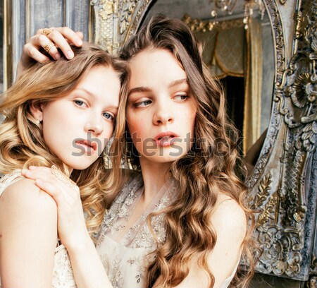 Stock photo: two pretty twin sister blond curly hairstyle girl in luxury house interior together, rich young peop