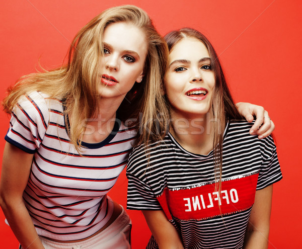 Stock photo: two best friends teenage girls together having fun, posing emotional on red background, besties happ