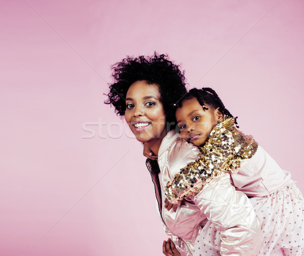 young pretty african-american mother with little cute daughter hugging, happy smiling on pink backgr Stock photo © iordani