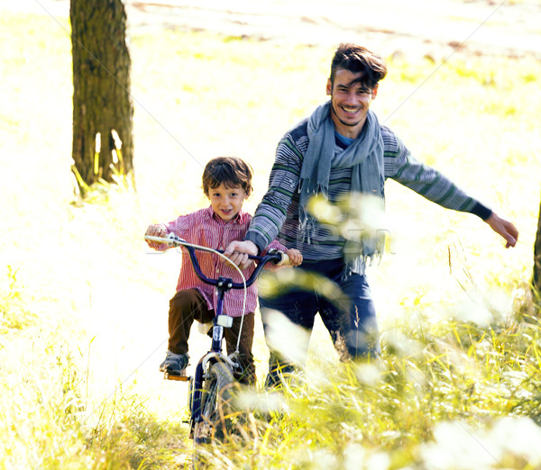 father learning his son to ride on bicycle outside, real happy f Stock photo © iordani