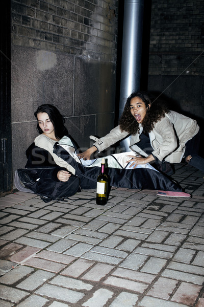 young poor ttenage girl sitting at dirty wall on floor with bottle of vine, poor refugee alcoholic,  Stock photo © iordani