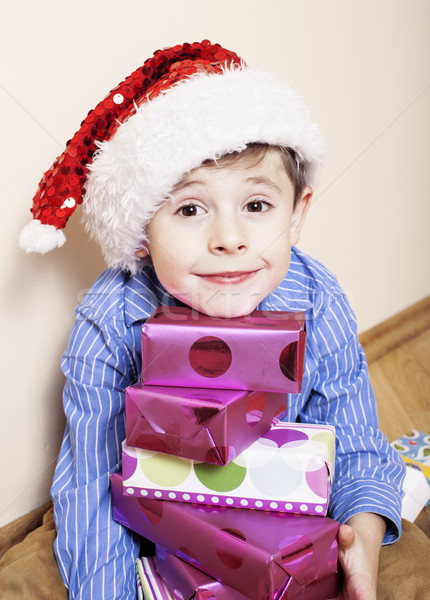 little cute boy with Christmas gifts at home. close up emotional face on boxes in santas red hat Stock photo © iordani