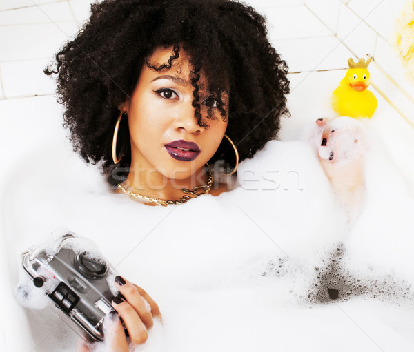 young afro-american teen girl laying in bath with foam, wearing  Stock photo © iordani