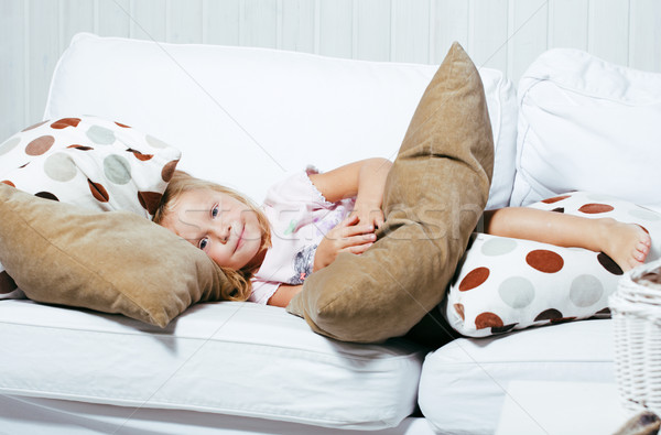 little cute blonde norwegian girl playing on sofa with pillows, lifestyle people concept Stock photo © iordani