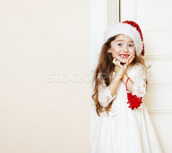 Stock photo: little cute girl in santas red hat waiting for Christmas gifts. 