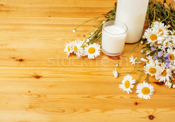 Simply stylish wooden kitchen with bottle of milk and glass on table, summer flowers camomile, healt Stock photo © iordani