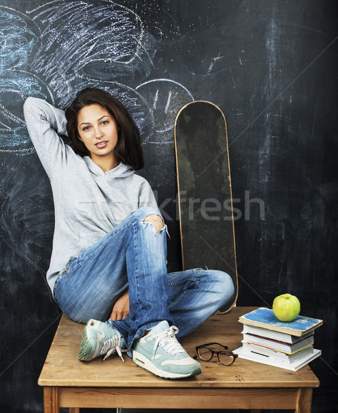 young cute teenage girl in classroom at blackboard seating on table smiling, modern hipster concept, Stock photo © iordani