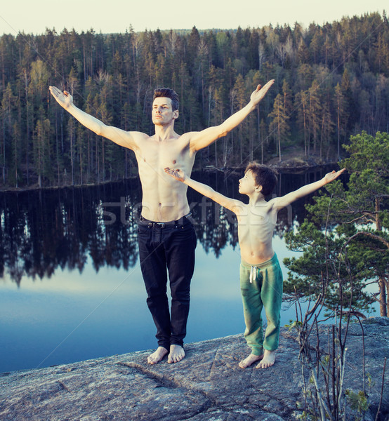 middle age man with little cute son doing sport yoga on the top of the mountain together, happy fami Stock photo © iordani