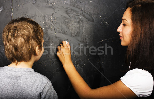 little cute boy with young teacher in classroom studying at blackboard, lifestyle education people c Stock photo © iordani