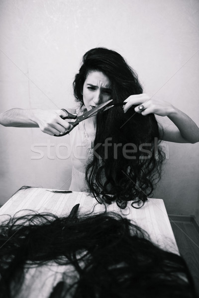 beauty girl cuting her hair in empty fearing room with cutted hair, halloween creepy celebration art Stock photo © iordani