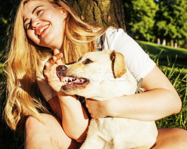 young attractive blond woman playing with her dog in green park  Stock photo © iordani