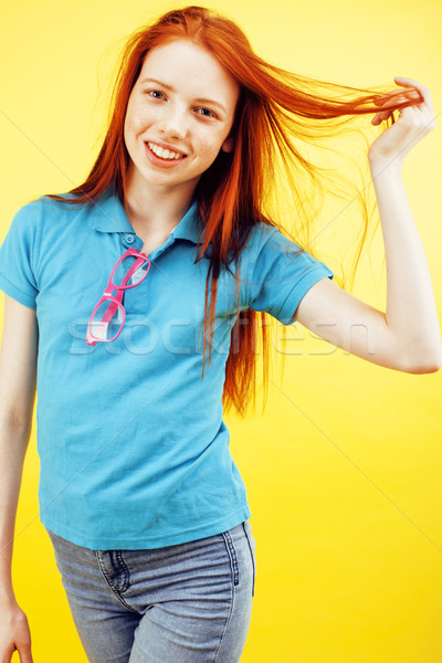 young pretty red hair teenage hipster girl posing in glasses emotional happy smiling on yellow backg Stock photo © iordani