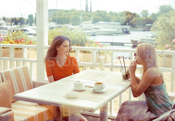 portrait of two pretty modern girl friends in cafe open air interior drinking and talking, having ch Stock photo © iordani