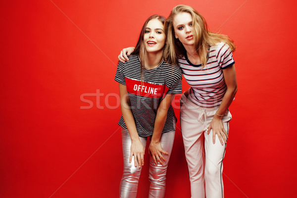 Stock photo: two best friends teenage girls together having fun, posing emotional on red background, besties happ