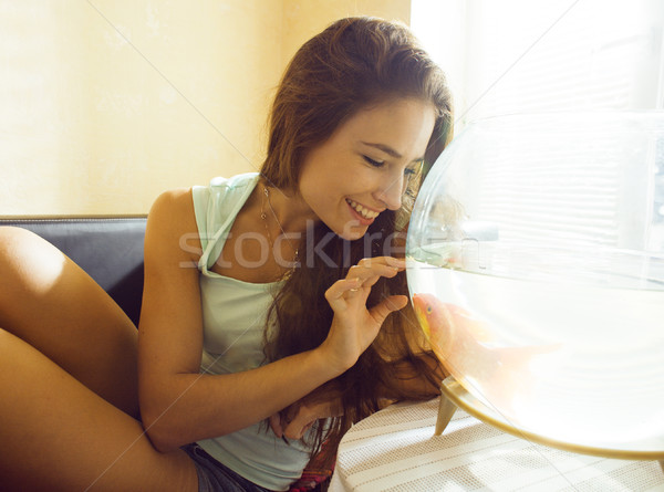 pretty woman playing with goldfish at home, sunlight morning Stock photo © iordani