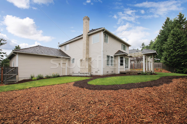 Image of Large beige house with empty backyard during spring