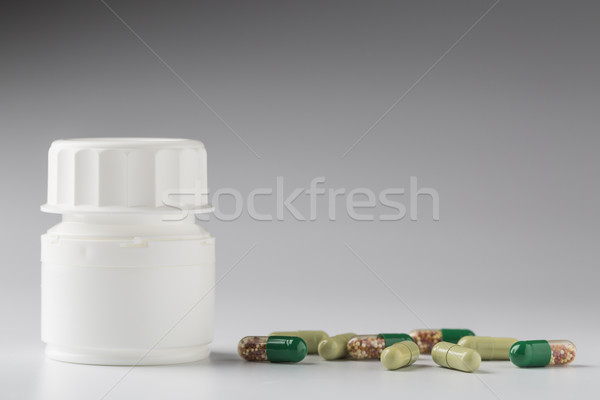 Medicine white bottle and various colorful capsules Stock photo © ironstealth