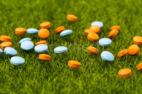 Scattered orange and blue round pills on the green grass Stock photo © ironstealth