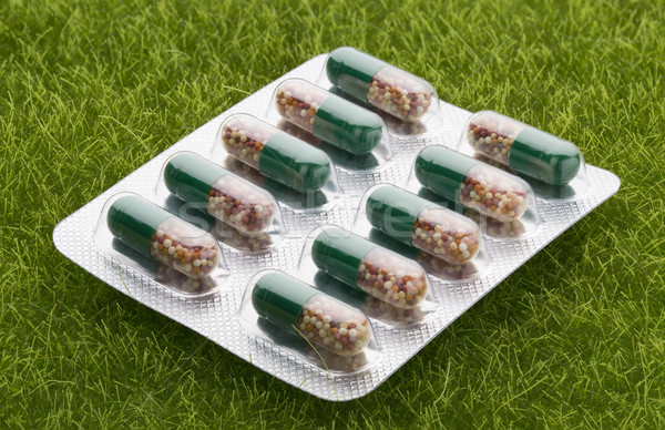 Green pills in a blister pack on gree grass background Stock photo © ironstealth