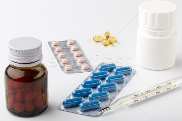 The treatment at home. Glass thermometer and various pills bottles Stock photo © ironstealth
