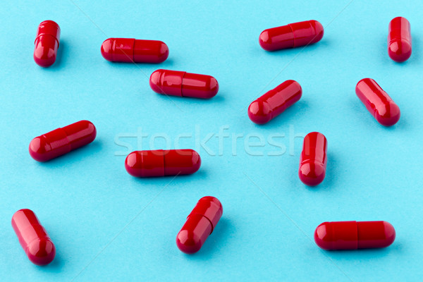 Drug red capsules scattered on the blue background Stock photo © ironstealth