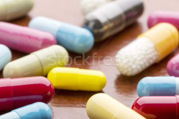 Various colorful medicine capsules on wooden background Stock photo © ironstealth