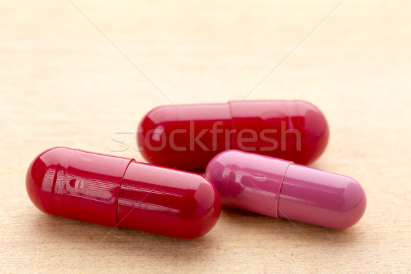 Three red capsules on the wooden table Stock photo © ironstealth