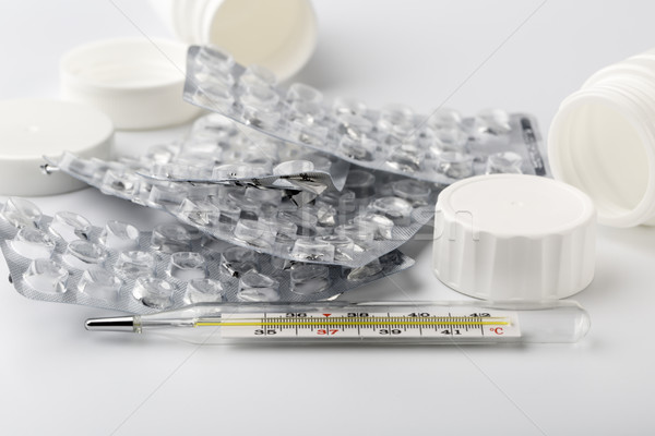 Stock photo: The treatment at home.Glass thermometer and used pills packaging