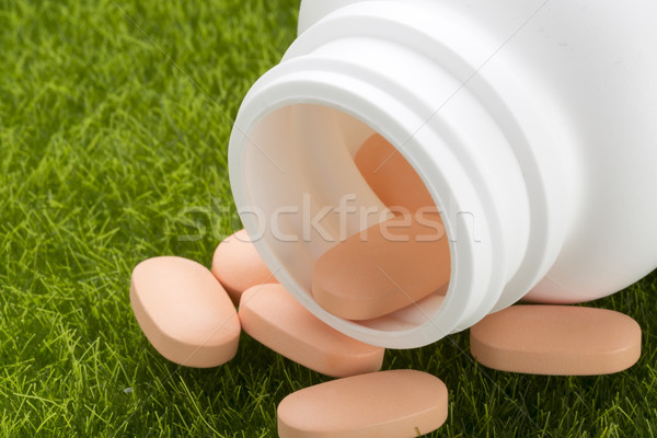 Close up pill bottle spilling orange pills on to grass Stock photo © ironstealth