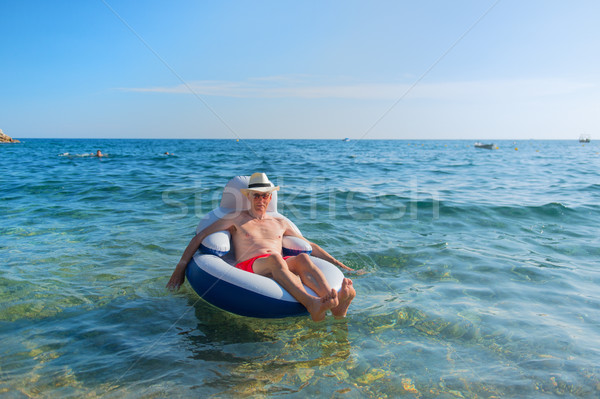 Senior man floating in sea Stock photo © ivonnewierink