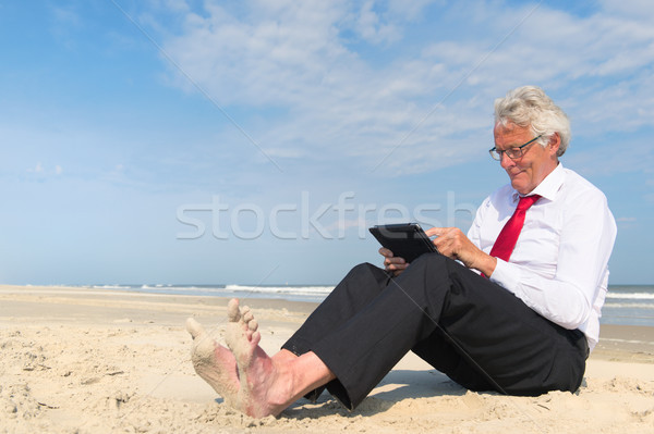 Business man working on tablet at the beach Stock photo © ivonnewierink