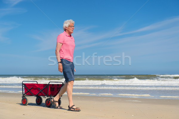Stock photo: Senior man walking with red cart at beach