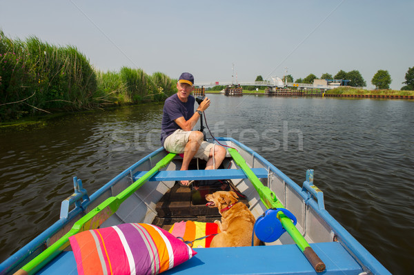 Senior man with dog in boat Stock photo © ivonnewierink