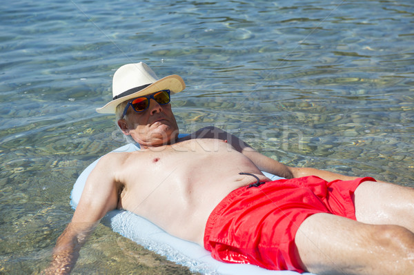 Nyugdíjas férfi lebeg ágy tenger víz Stock fotó © ivonnewierink
