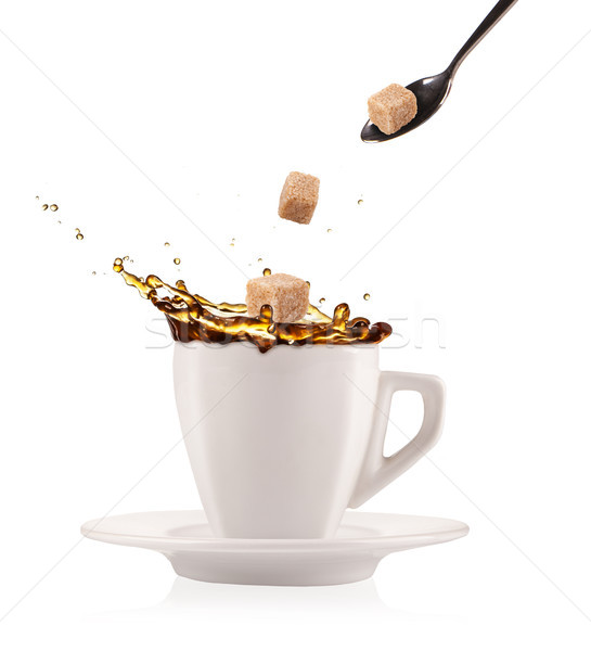 Stock photo: Coffee splashing out of cup with flying sugar cubes, isolated on white background