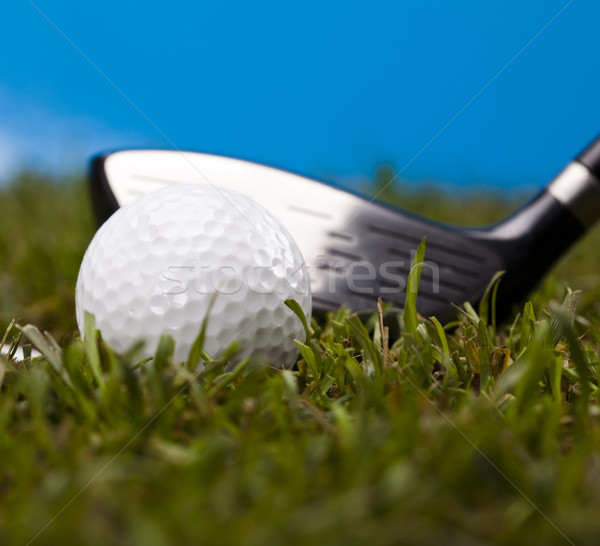 Stock photo: Golf ball on green grass over a blue background 