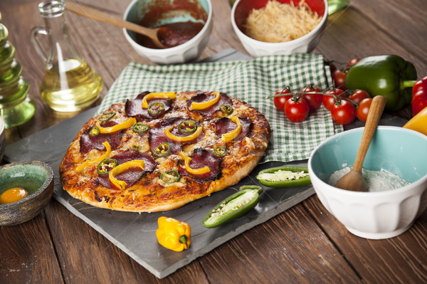 Tasty pizza, tomatoes and others ingredients on a wooden backgro Stock photo © JanPietruszka