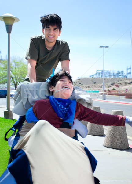 Big brother pushing happy disabled boy in wheelchair Stock photo © jarenwicklund
