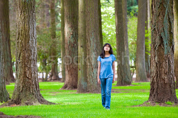 Young teen biracial girl walking under tall trees Stock photo © jarenwicklund