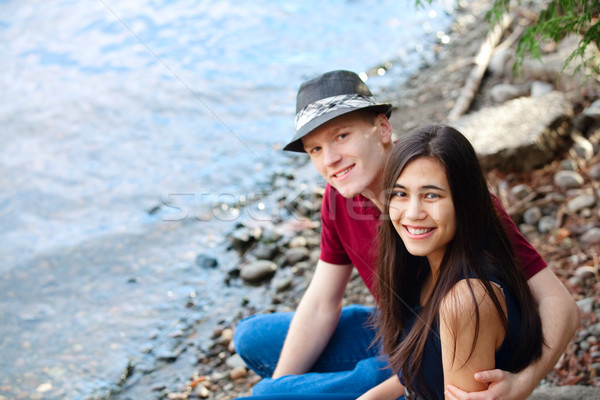 Beautiful young interracial couple sitting together by lake shor Stock photo © jarenwicklund