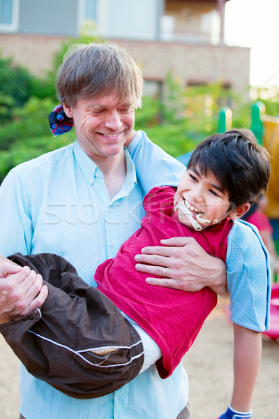 Stock photo: Caucasian father carrying biracial disabled son on playground