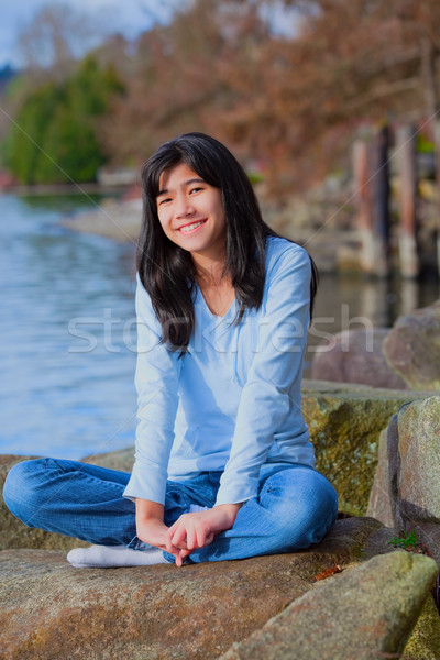 Young teen girl relaxing on large boulder along lake shore, smil Stock photo © jarenwicklund