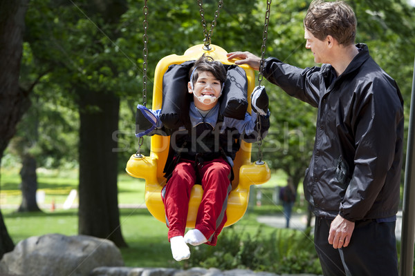 Father pushing disabled boy in special needs swing Stock photo © jarenwicklund